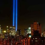New York City skyline at night with memorial lights.