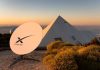 Satellite dish near pyramid-shaped building at sunset.