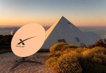 Satellite dish near pyramid-shaped building at sunset.