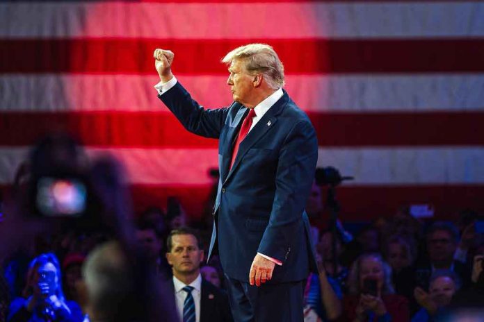 Person in suit with fist raised in front of flag.