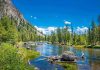 Mountain river landscape with trees and clear blue sky.