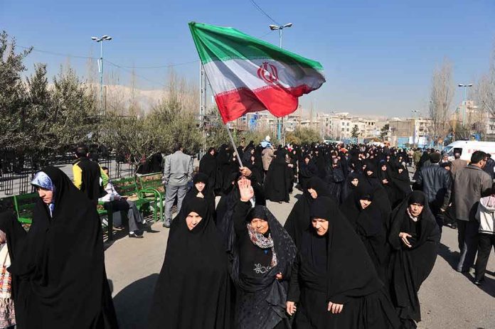 Group of women in black attire marching with an Iranian flag