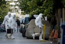 Investigators in hazmat suits carrying equipment cases.