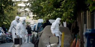 Investigators in hazmat suits carrying equipment cases.