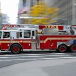 Red fire truck driving through city street crosswalk