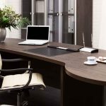 A modern office desk with a laptop, floral arrangement, and coffee cups