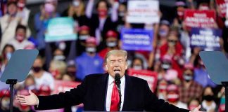 Person speaking at a podium during a rally.