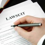 One Lawsuit Could Redefine Free Speech Hand holding pen, filling out lawsuit form.