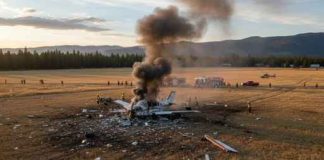 A crashed airplane emitting smoke with emergency responders on site