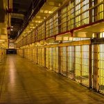 Missouri Drops Bomb on Prison Care Empty hallway between rows of prison cells.