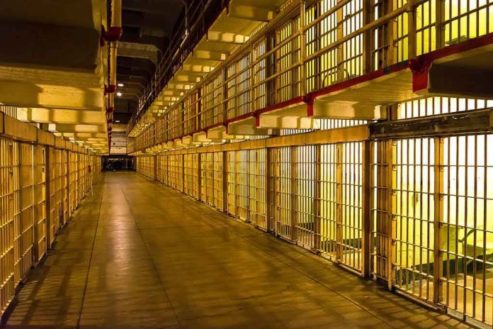 Empty hallway between rows of prison cells.