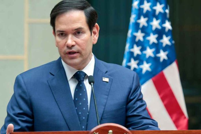 Marco-Rubio-speaks_2581735273 A man in a blue suit speaking into a microphone with an American flag in the background