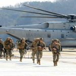 Iran Hits Jordan Base — Americans Killed Soldiers disembark and walk past a large military helicopter