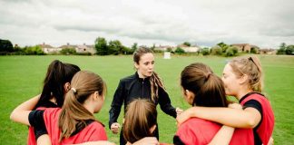Coach talks to youth team in a huddle on a field