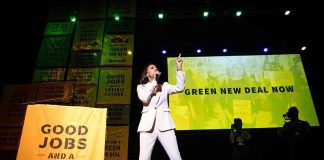Speaker in white suit on stage at climate rally