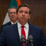 man in suit at podium with microphones