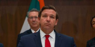 man in suit at podium with microphones