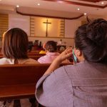 Church Leaders Shielded Convict Near Kids people seated in church pews facing a cross