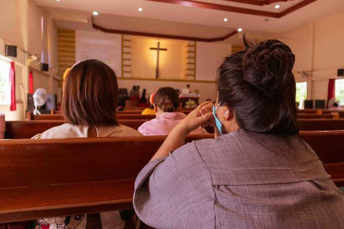 shutterstock_1773600770 people seated in church pews facing a cross