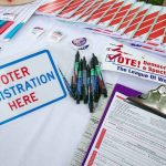 Prison Threats Over Voter Rolls Voter registration table with forms, pens, and informational materials