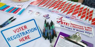 Voter registration table with forms, pens, and informational materials