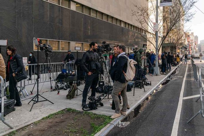 news crews set up cameras on a city sidewalk outside a courthouse
