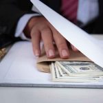 Record Cash Floods NYC Businessperson hides cash in an envelope under documents