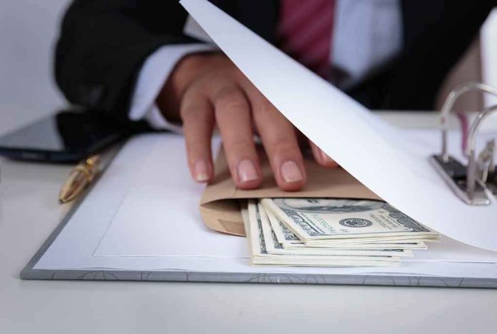 shutterstock_708324106 Businessperson hides cash in an envelope under documents