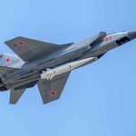 fighter jet with missile flying against a clear blue sky