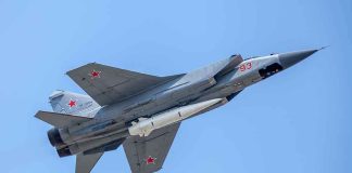 fighter jet with missile flying against a clear blue sky