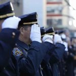 uniformed police officers salute in formation outdoors