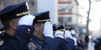 uniformed police officers salute in formation outdoors