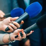 Reporters holding colorful microphones
