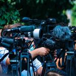 Fake NBA Star Nabs $90K BMW TV news cameras crowding together at an outdoor event