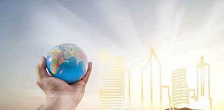 Hand holding a small globe in front of a glowing city skyline outline
