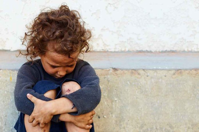 child sitting on ground with arms wrapped around knees