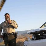 Trooper Killed In Vehicle Explosion Police officer at crash scene near damaged white car