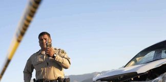 Police officer at crash scene near damaged white car