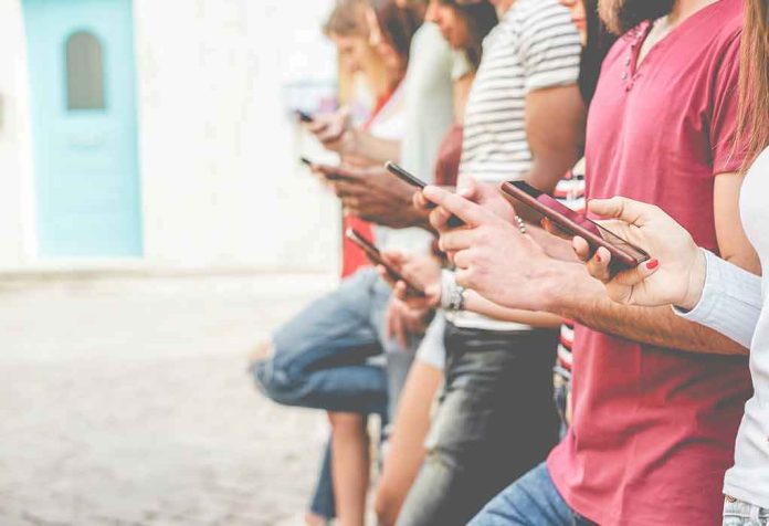 shutterstock_1109614925 Group of people using smartphones while standing in a row