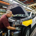 Trump Calls Inflation ‘Hoax’ — Crowd Erupts factory worker assembling a pickup truck on an automotive production line