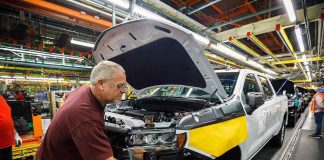 factory worker assembling a pickup truck on an automotive production line