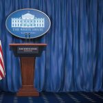 White House press briefing podium with U.S. flag and blue curtain