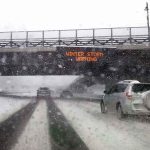 Historic Freeze Is Bearing Down cars driving on snowy highway under bridge during winter storm