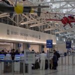 ICE Turns Airports Into New Front Line for Immigration Arrests airport security checkpoint with passengers and hanging vintage airplanes