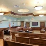 Woman Arrested for JUROR INTIMIDATION Empty courtroom with wooden benches and judge's bench