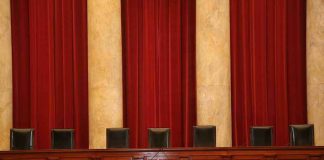 Empty courtroom bench with red curtains and leather chairs