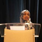 Deportation Talk Explodes About Illhan Omar Woman in hijab speaking at a podium
