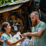 Musk Accused Of ‘Killing’ Children Volunteers distribute relief supplies to a woman outdoors