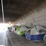 Tents lined up under a concrete overpass