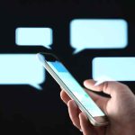 44 Lawmakers Had Private Messages Hacked Hand holding smartphone with chat bubbles on dark background